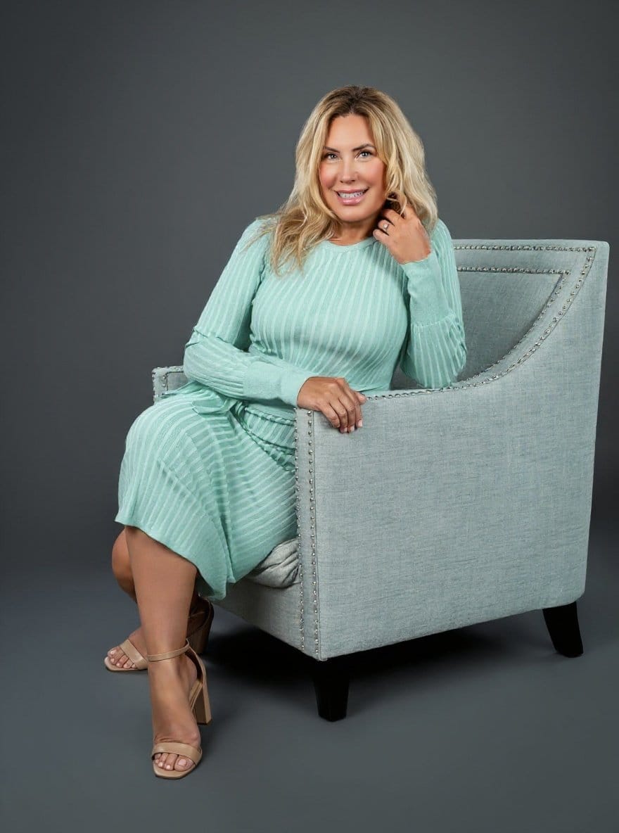 Dodie Kendall seated and smiling warmly in a soft aqua dress. QHHT Practitioner in Stuart, FL